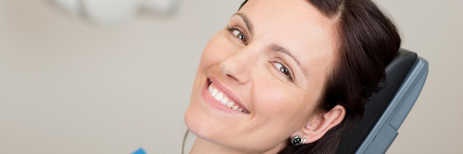 woman with earrings sitting in dental exam chair l dentist nola