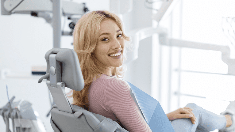Female patient sitting on a dental chair smiling after root canal treatment in New Orleans