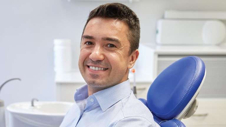 Smiling male patient on a blue dental chair in New Orleans